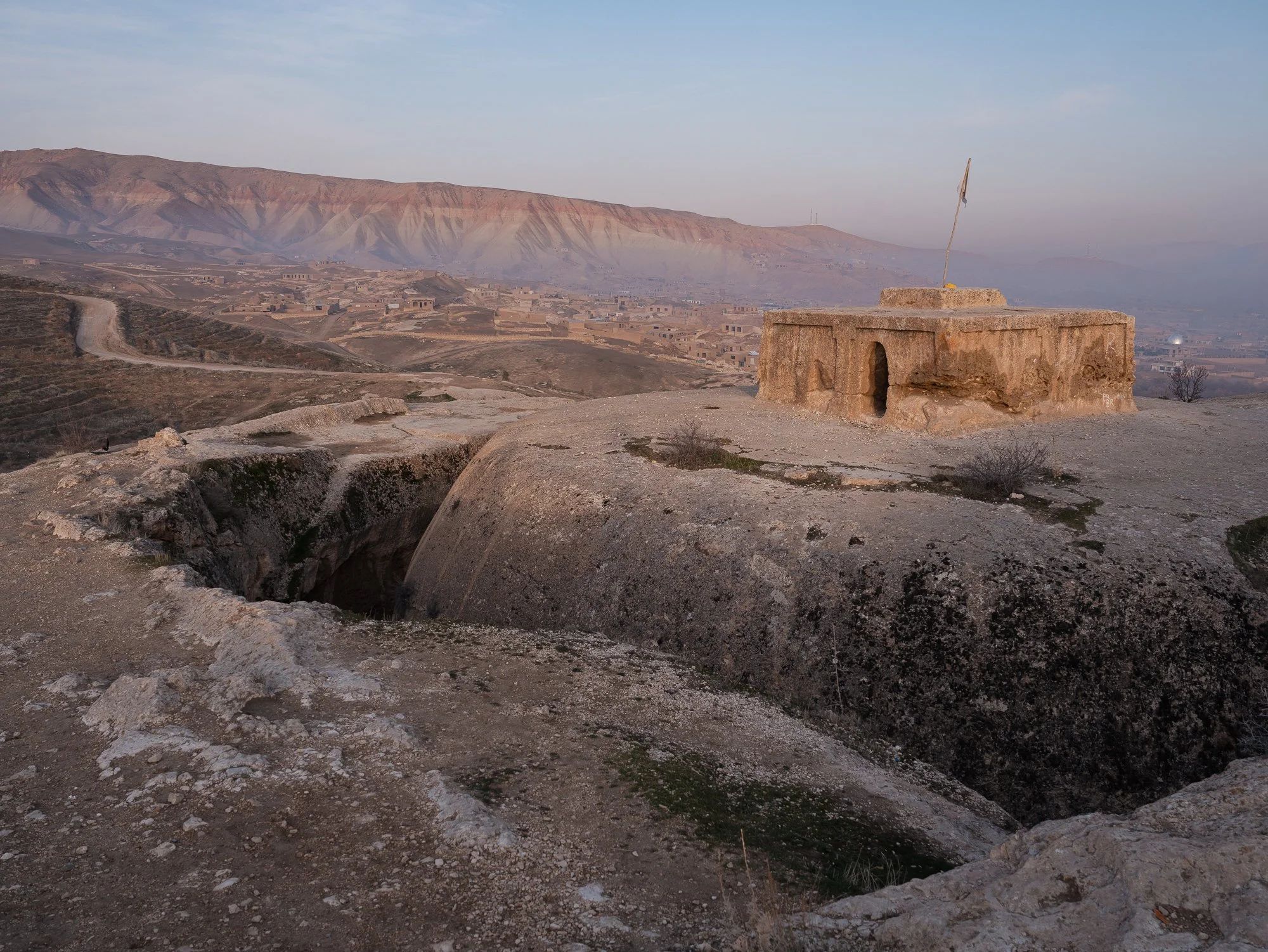 The remains of 'Takht-E-Rustam' in the morning light. 

The circular stupa is  hollowed out of solid rock, surrounded by a trench-like corridor that pilgrims would have used for ritual circumambulation. From this central monument, a network of hand-c