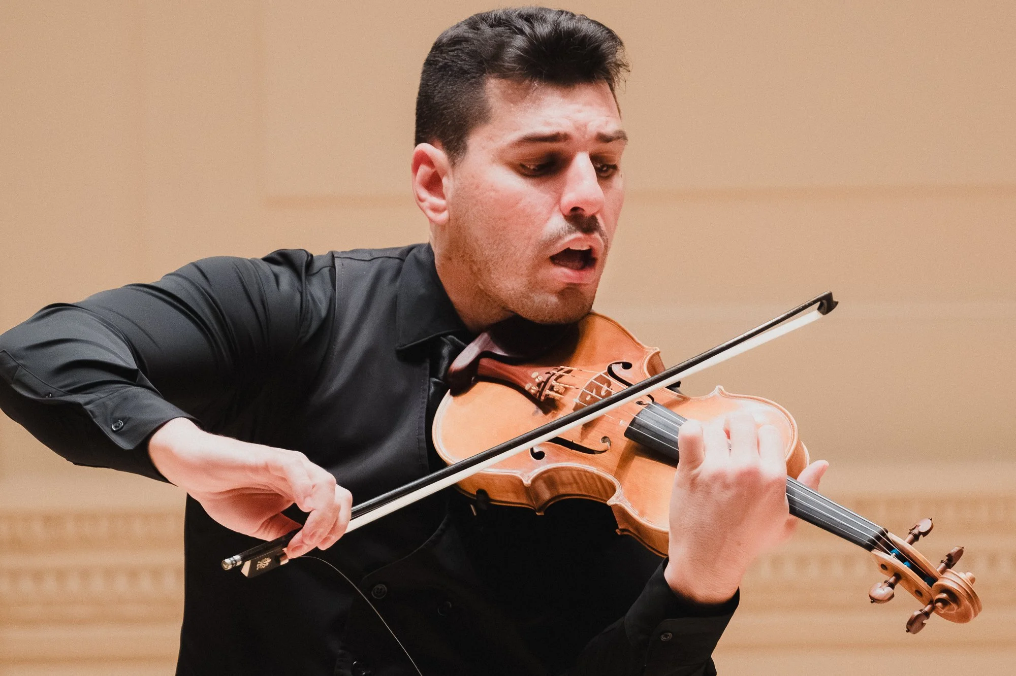 Close-up of violinist mid-performance at Weill Recital Hall, bow lifted with expressive open-mouthed intensity