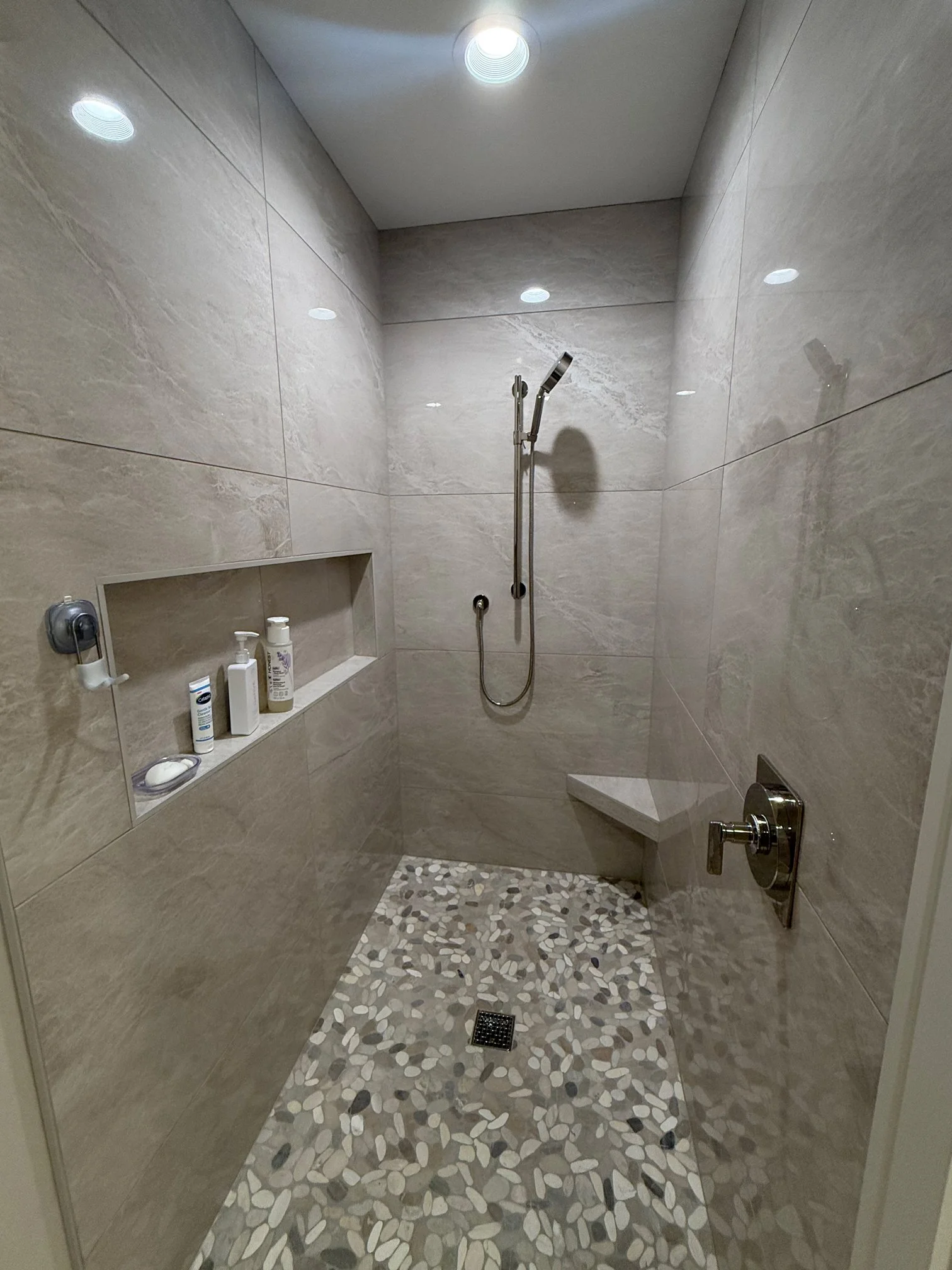 Modern shower with pebble tile flooring in luxury bath