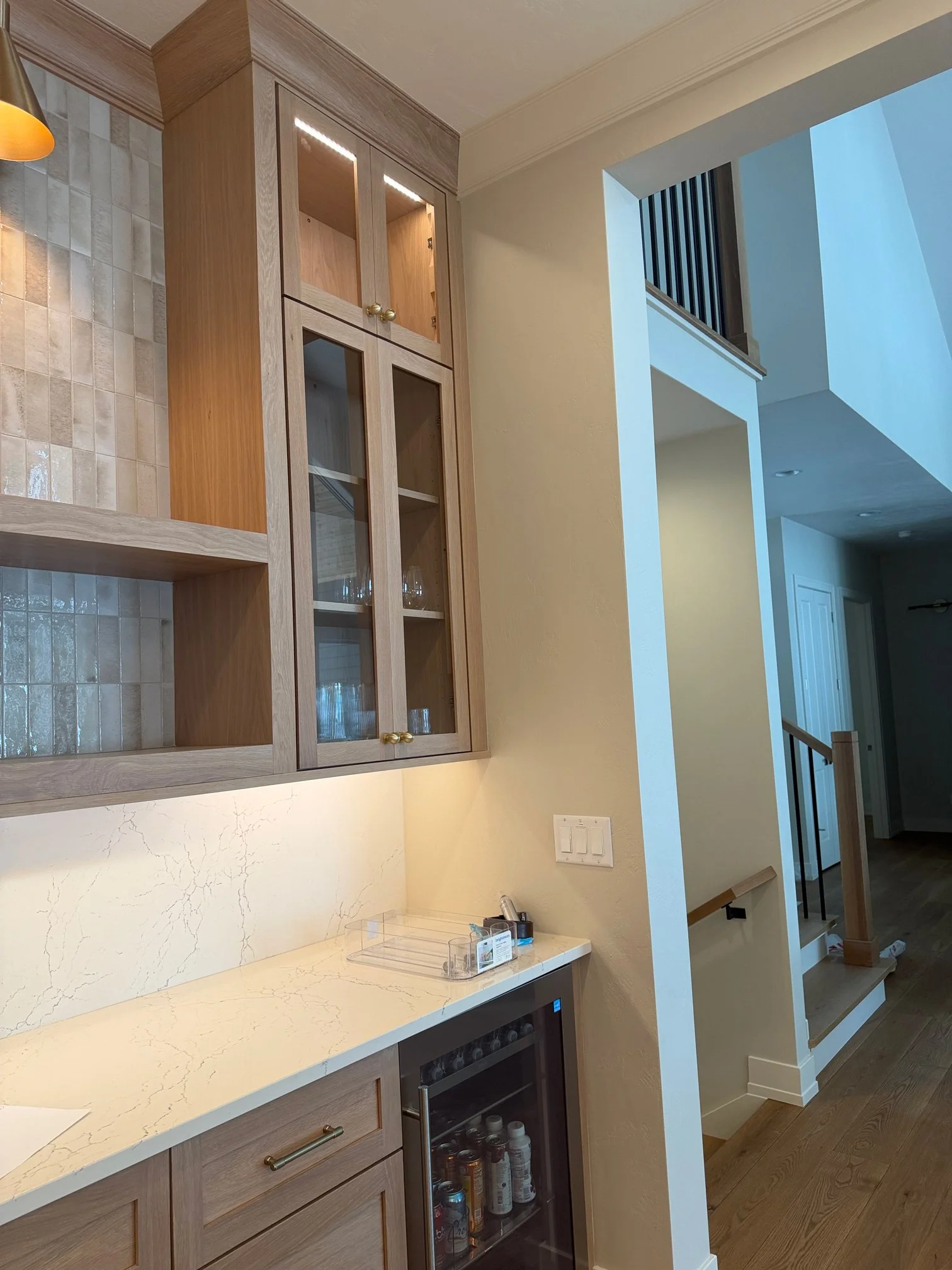 Wet bar with wine fridge near open staircase