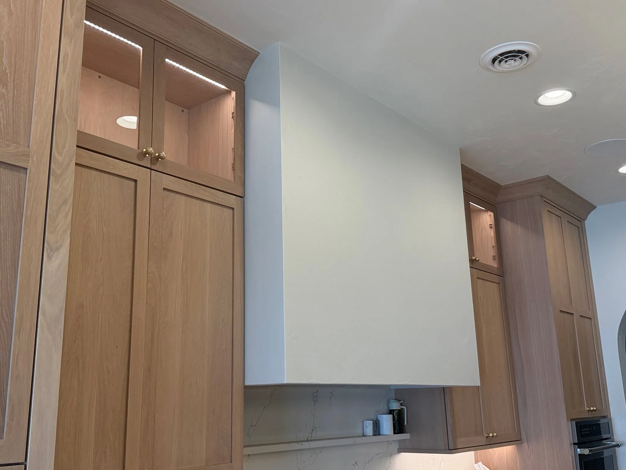 Wide-angle view of kitchen range hood and cabinetry