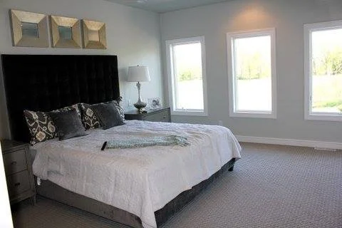 Bedroom with three windows and bed