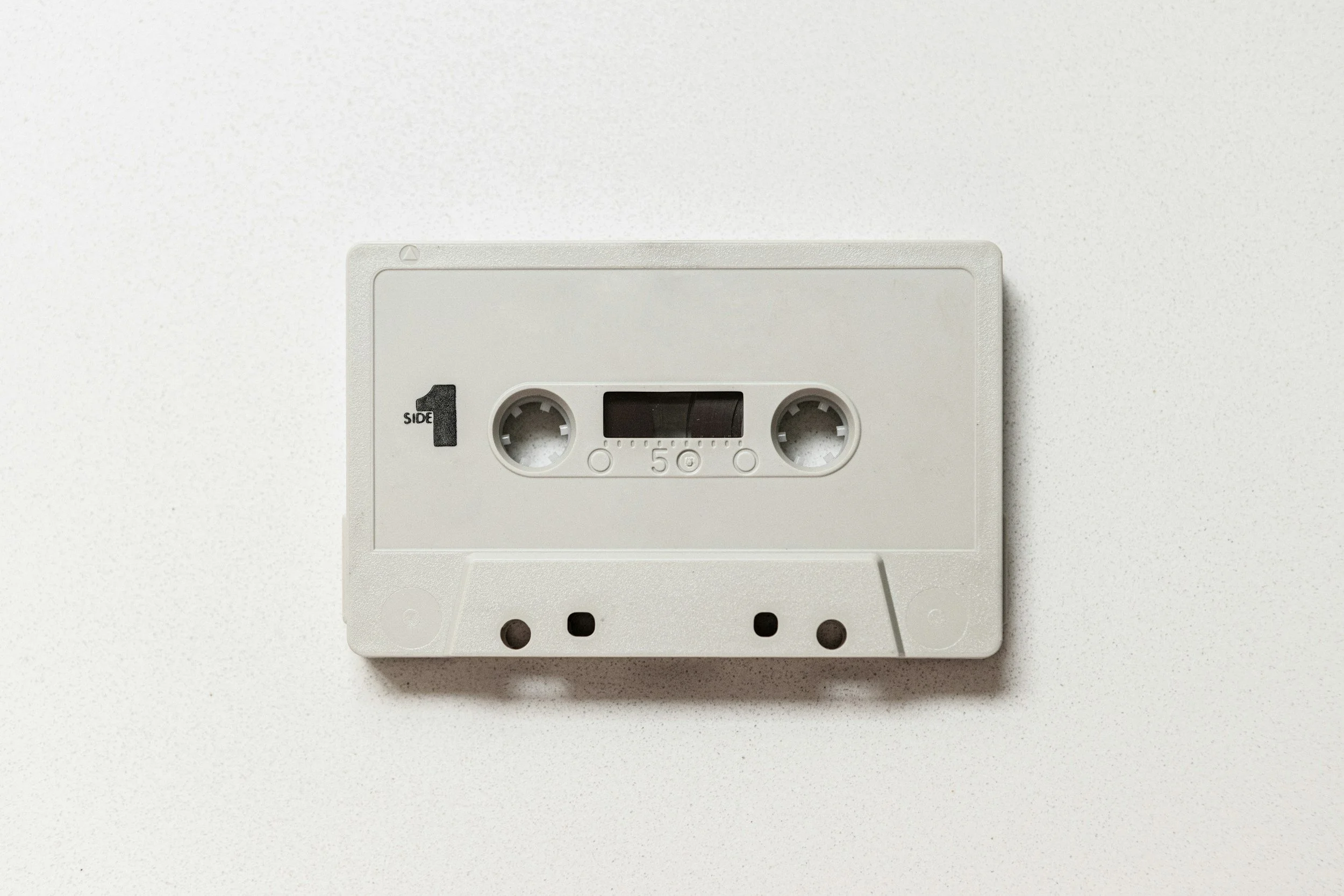 A blank cassette tape with an empty label in the center, placed on a white surface.