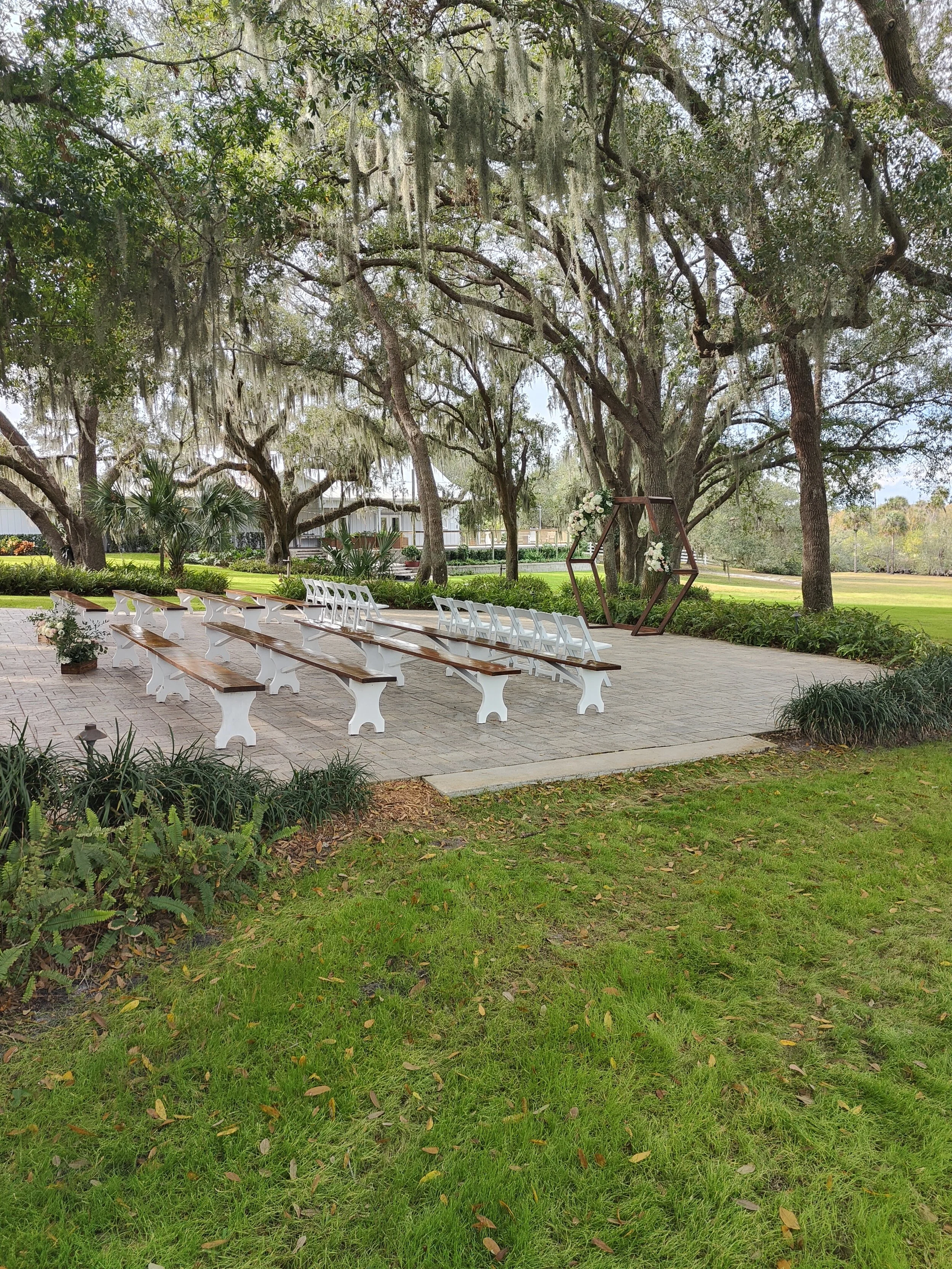 Shaded outdoor ceremony space at Up the Creek Farms in Malabar Florida with brick aisle and white doors beneath live oak trees