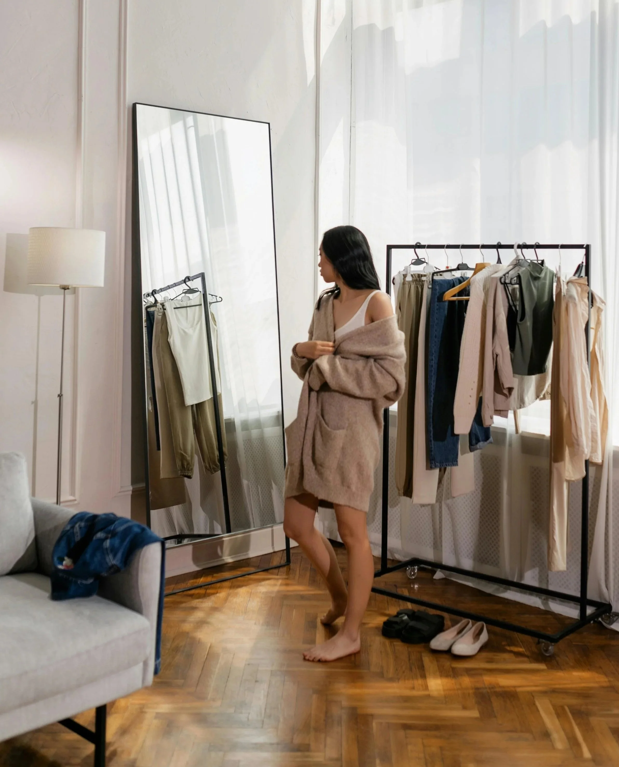 Photo by Alena Darmel of a woman trying on clothes in front of a clothing rack style