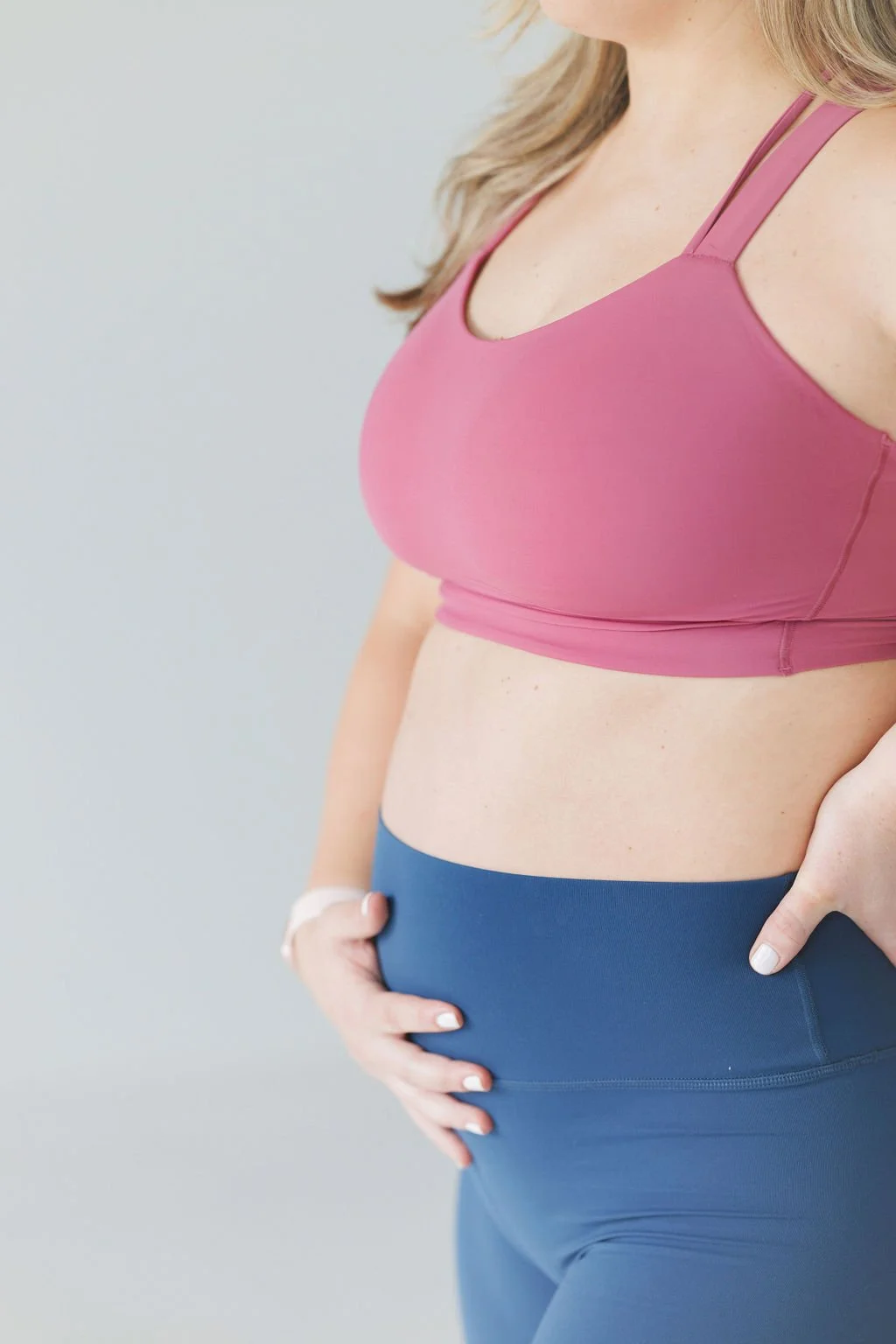 Pregnant woman holding belly in workout gear