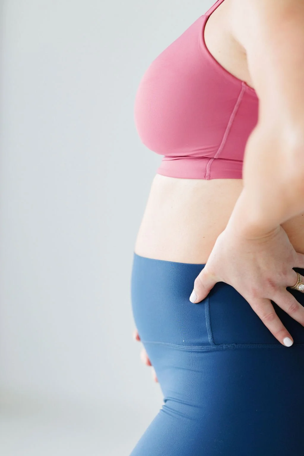pregnancy woman standing in exercise clothes holding belly