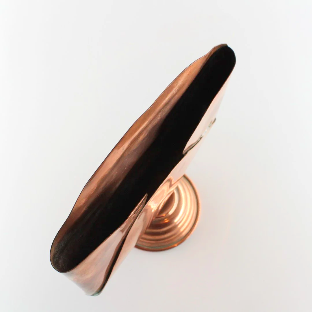 Vintage copper letter rack and mid century modern desk organiser with folded sculptural design and pedestal base against white background.
