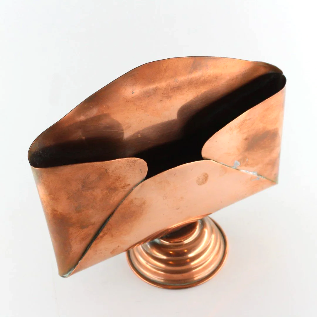 Vintage copper letter rack and mid century modern desk organiser with folded sculptural design and pedestal base against white background.