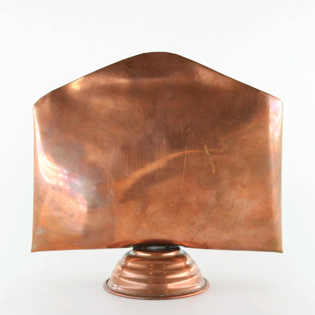 Vintage copper letter rack and mid century modern desk organiser with folded sculptural design and pedestal base against white background.