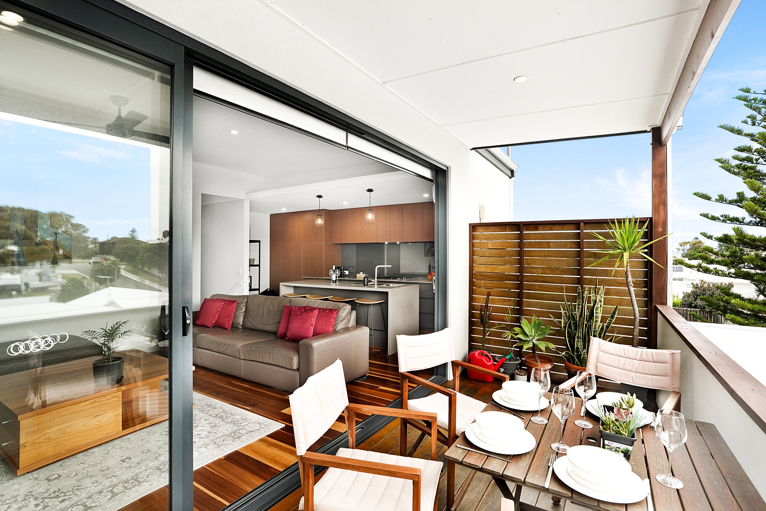 Outdoor Airbnb patio with green plants, wooden deck, two chairs and a table. Scarborough Perth | Hostyou