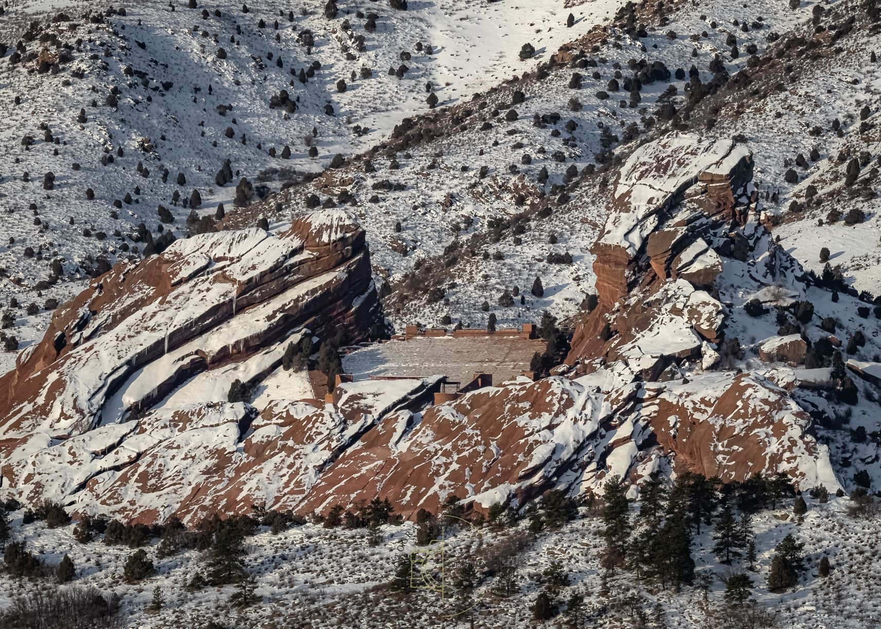 An image of Red Rocks Park and Amphitheater from a distance. With snowy contrast and sunrise light.