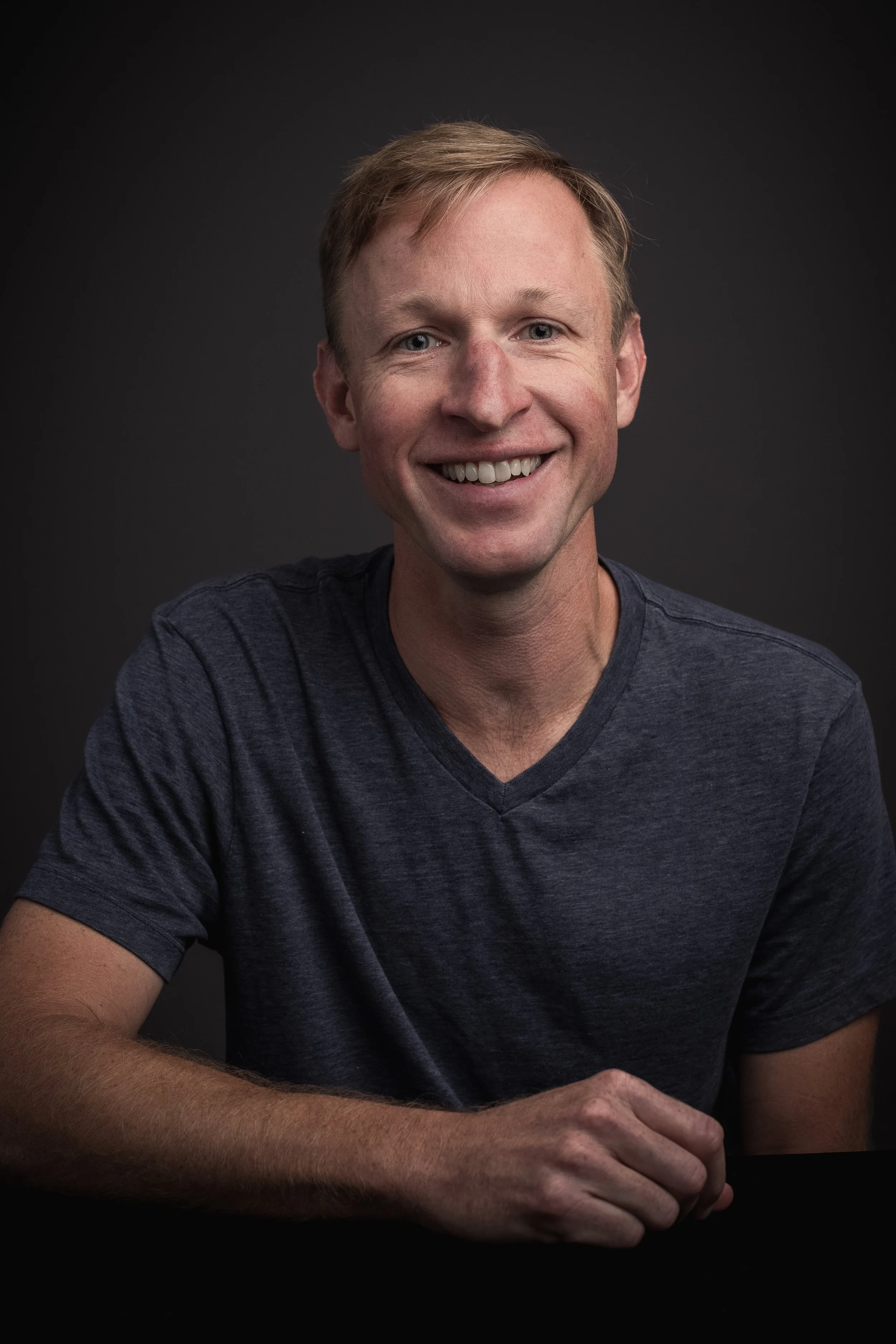Tim Hanson, President and Chief Investment Officer of Permanent Equity, in a navy t-shirt against a dark gray background.