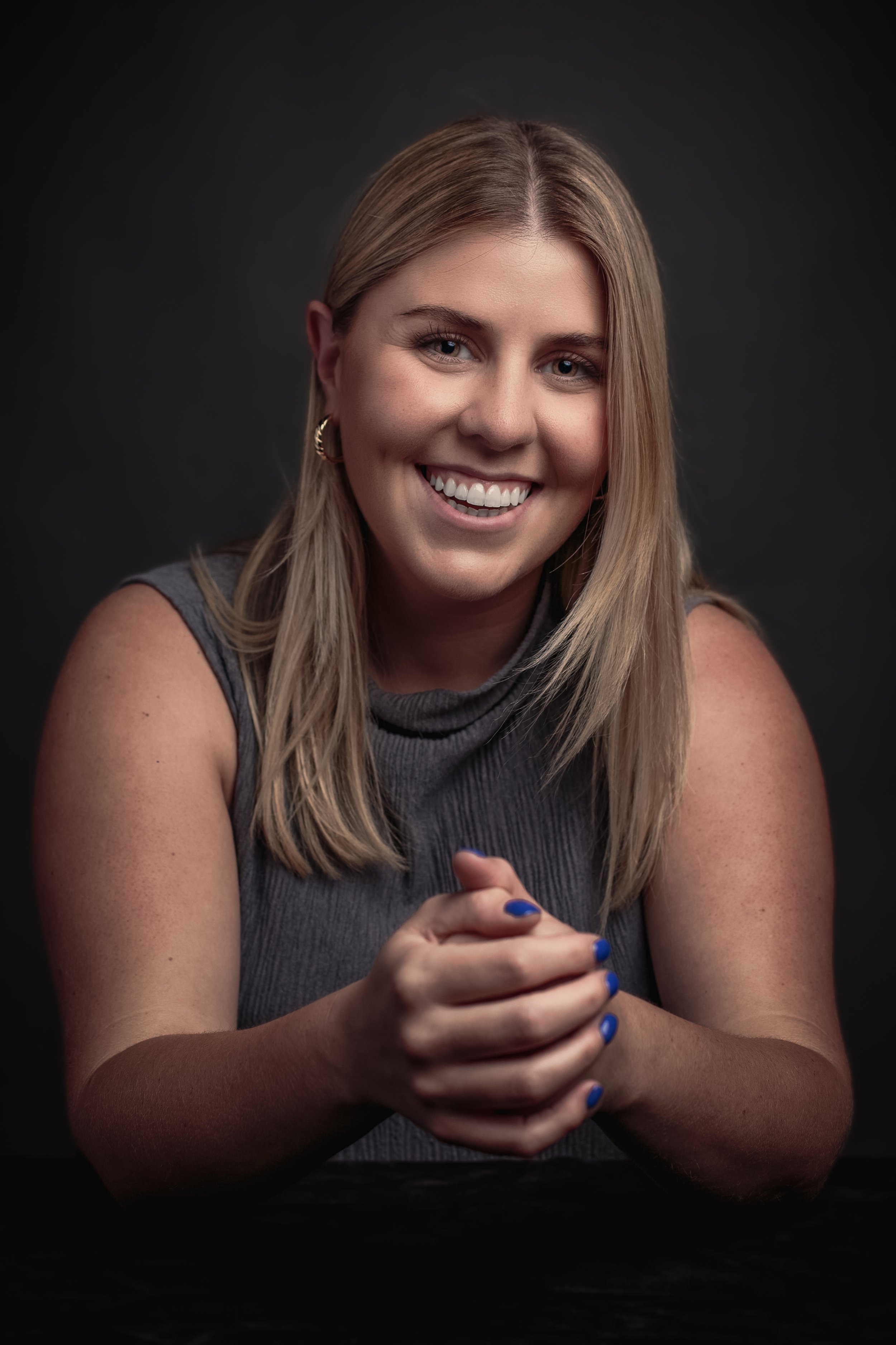 Holly Grajera, Business Development Associate at Permanent Equity, in a gray top against a dark gray background.