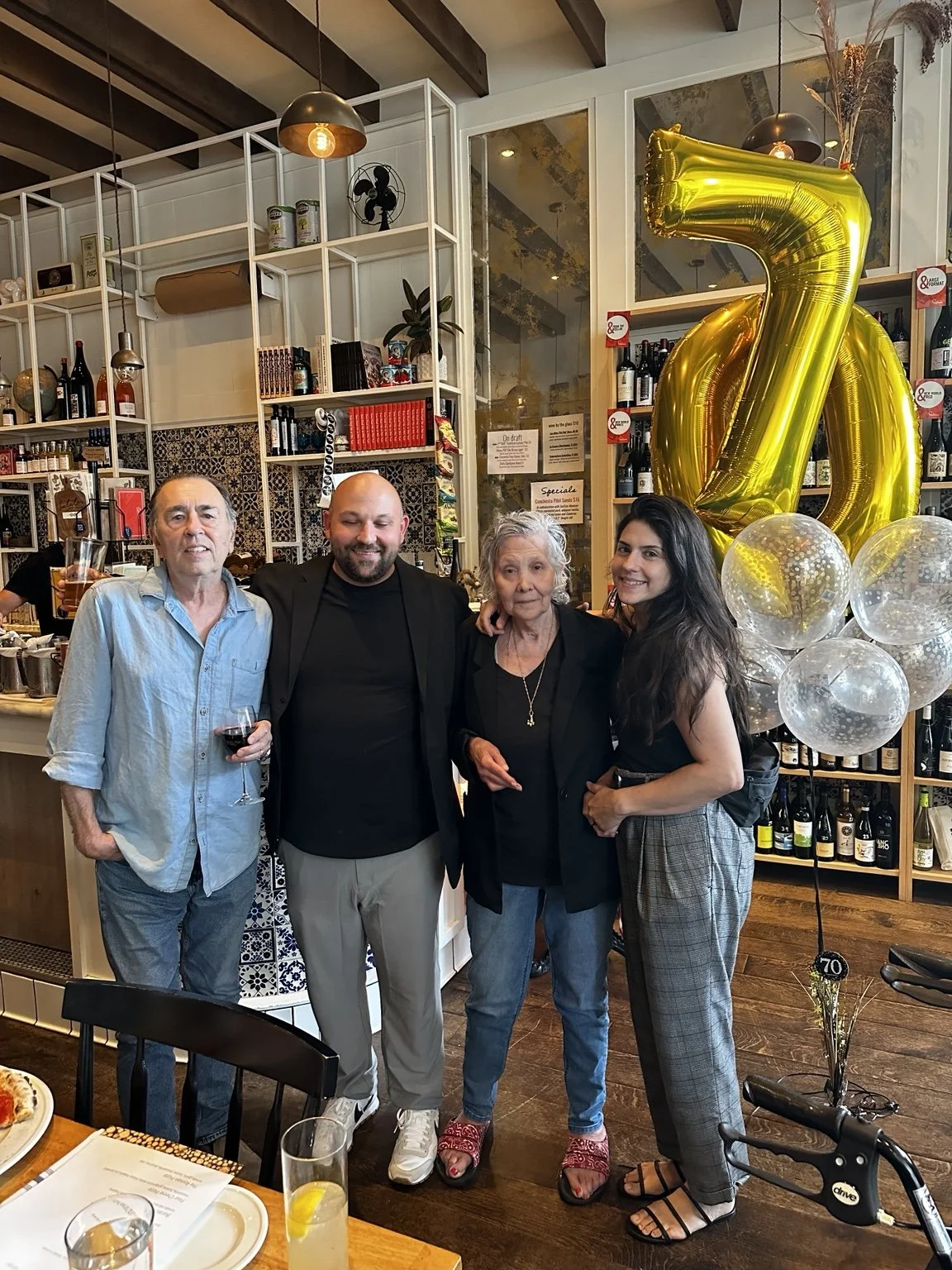 David Surkamp with loved ones at a birthday celebration, beside gold balloons.