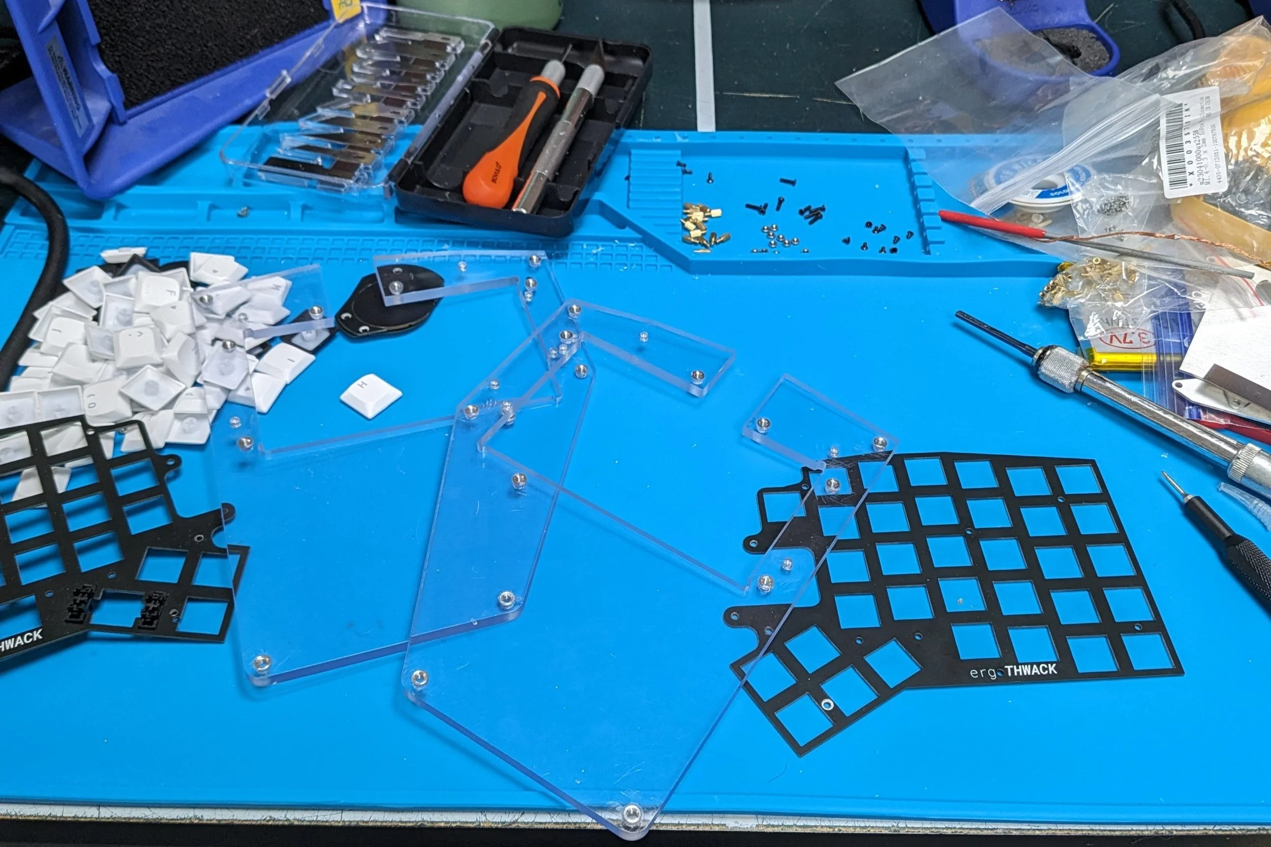 The top plates and CNC'ed polycarbonate base plates after heat-set inserts and deburring. The v1 ergoTHWACK uses a laser-cut steel base: stiffer, tapped holes instead of inserts, and less deburring.