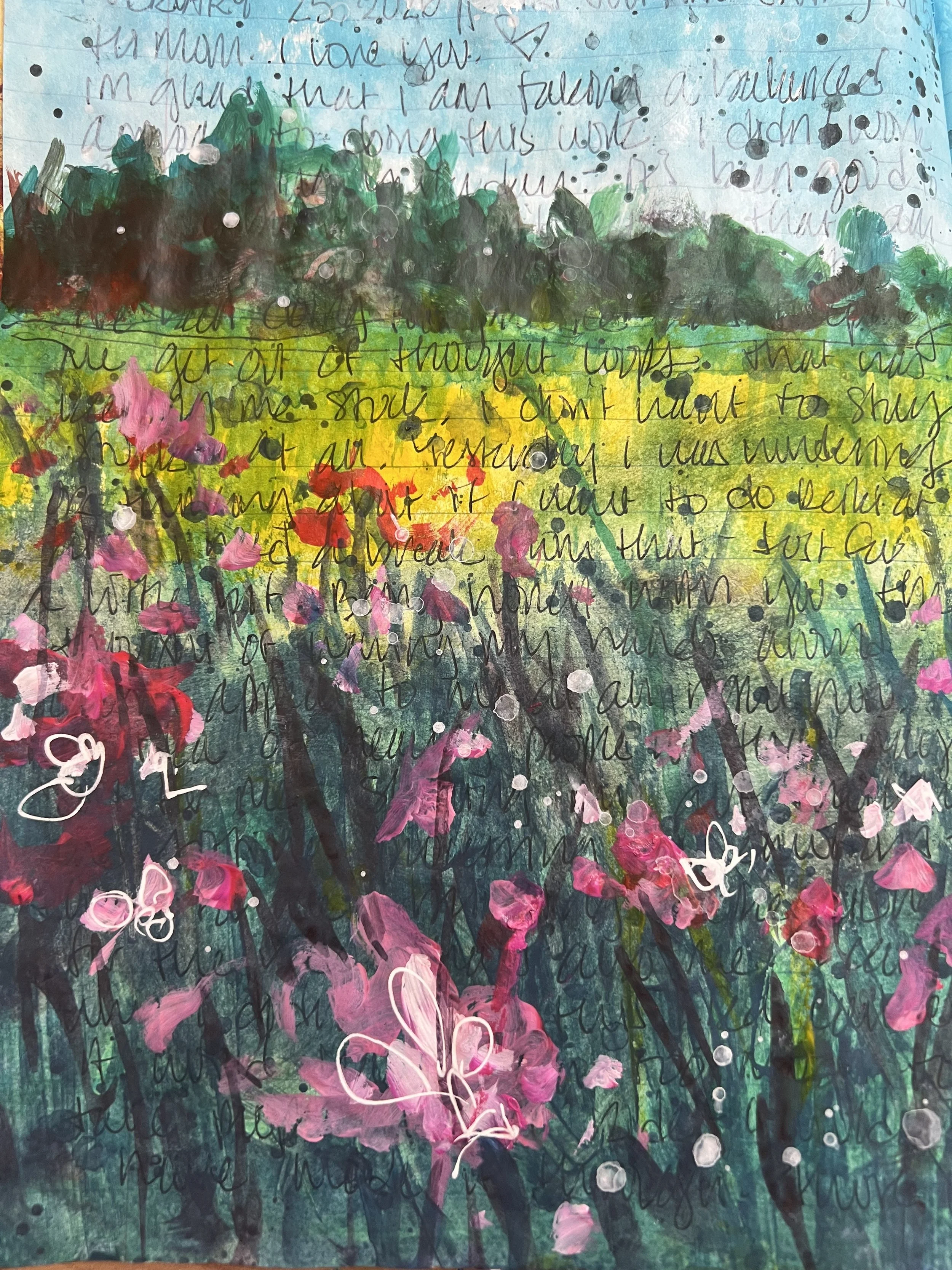 Close-up of an art journal painting showing a field of pink and red flowers with layered green and blue background, dark tree line, paint splatters, and handwritten journaling over the top.