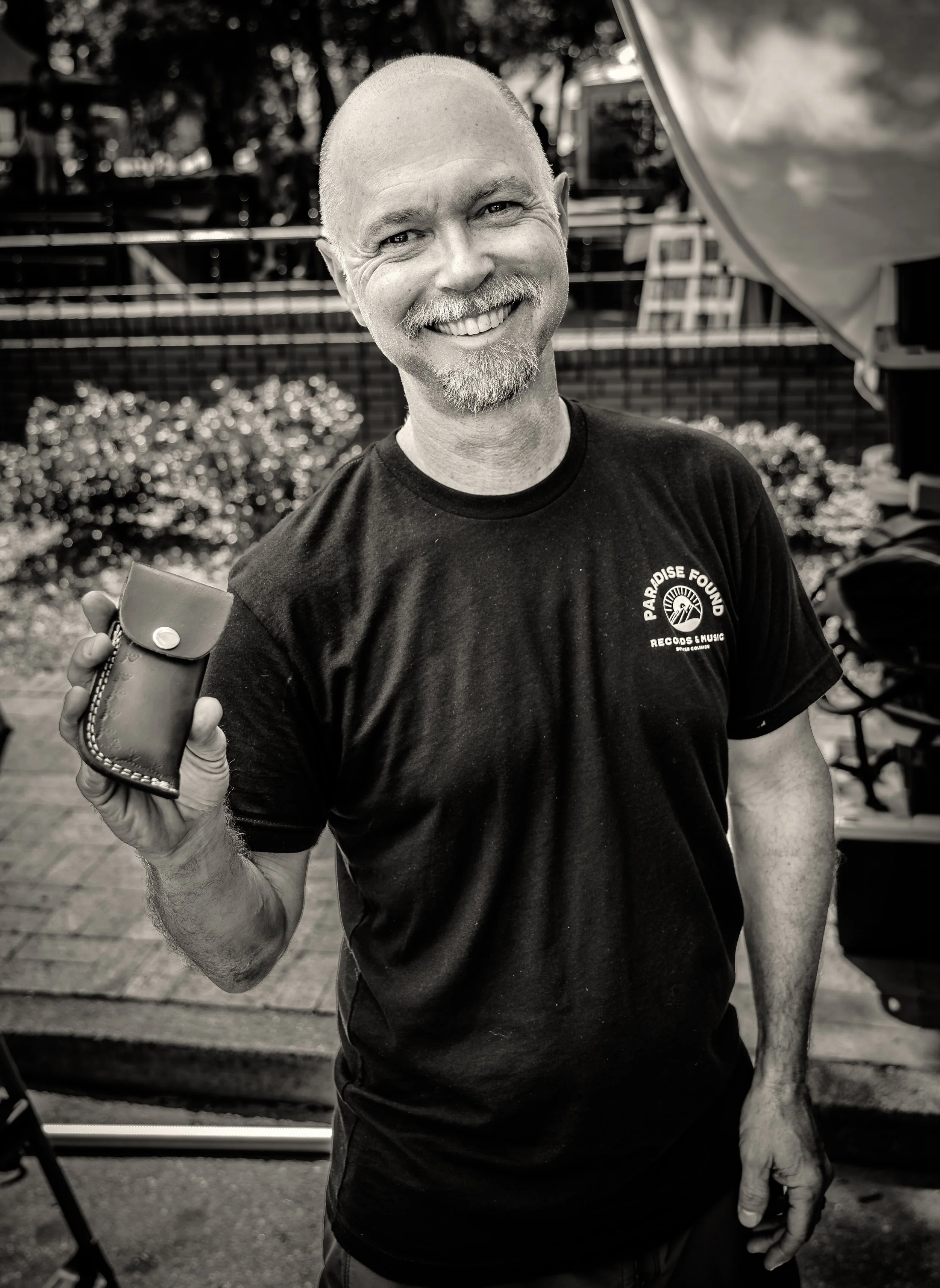 Smiling man holding small leather pouch outdoors
