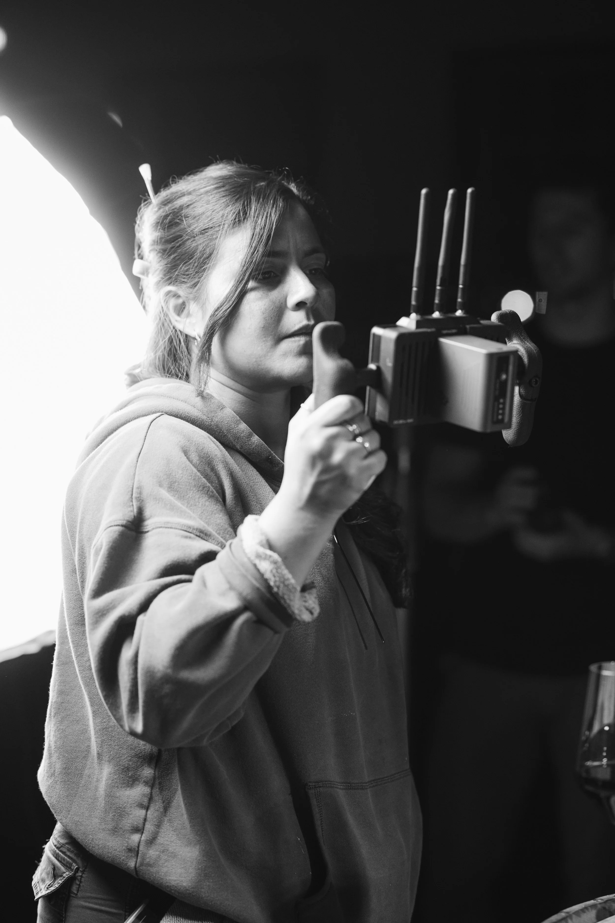 A woman in a hoodie holding a small wireless device with antennas, focusing on it.