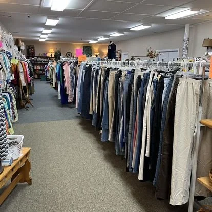 Clothing rack filled with various men's pants in a thrift store or clothing store.
