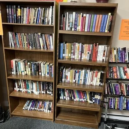 Two wooden bookshelves filled with various books in a library or bookstore.
