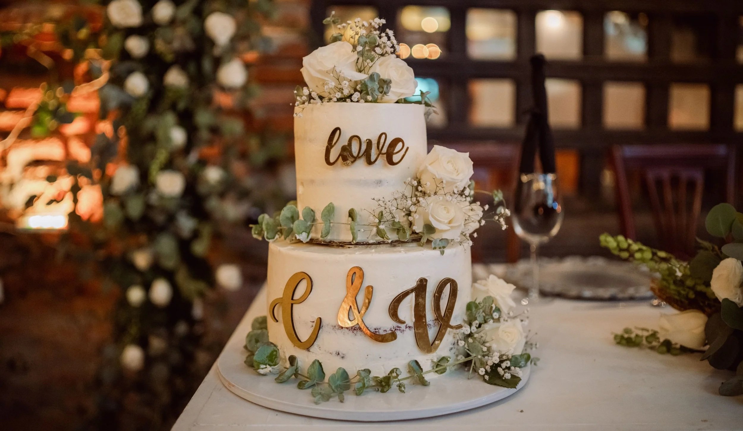 Three-tier white wedding cake adorned with pink and white roses.