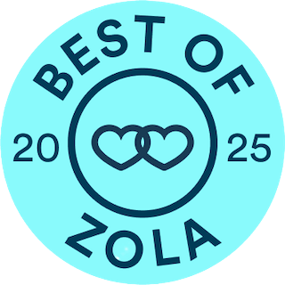 A circular badge with a blue background and dark blue text that says 'Best of Zola 2025', featuring two interlocked hearts at the center. Given to award winning wedding photographers.
