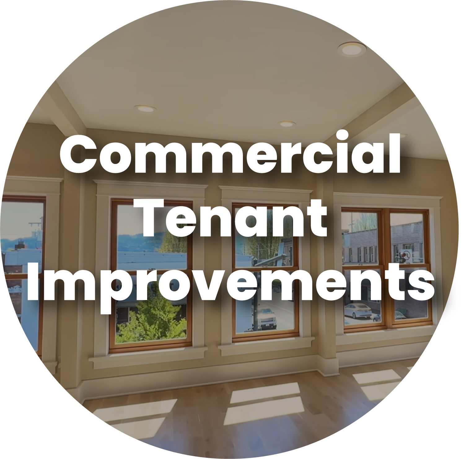 Interior of a room with multiple windows, cream-colored walls, and hardwood floors, with text overlay reading 'Commercial Tenant Improvements'.
