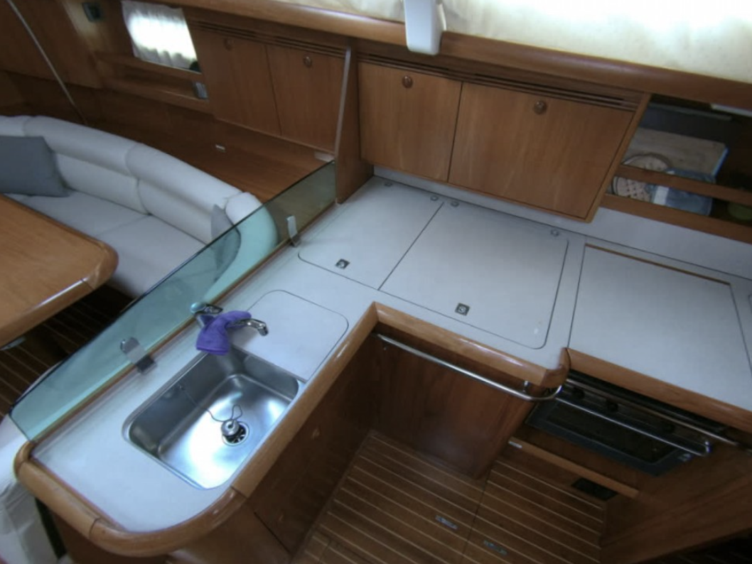 Interior of a boat kitchen with sink, stove, and wooden cabinets