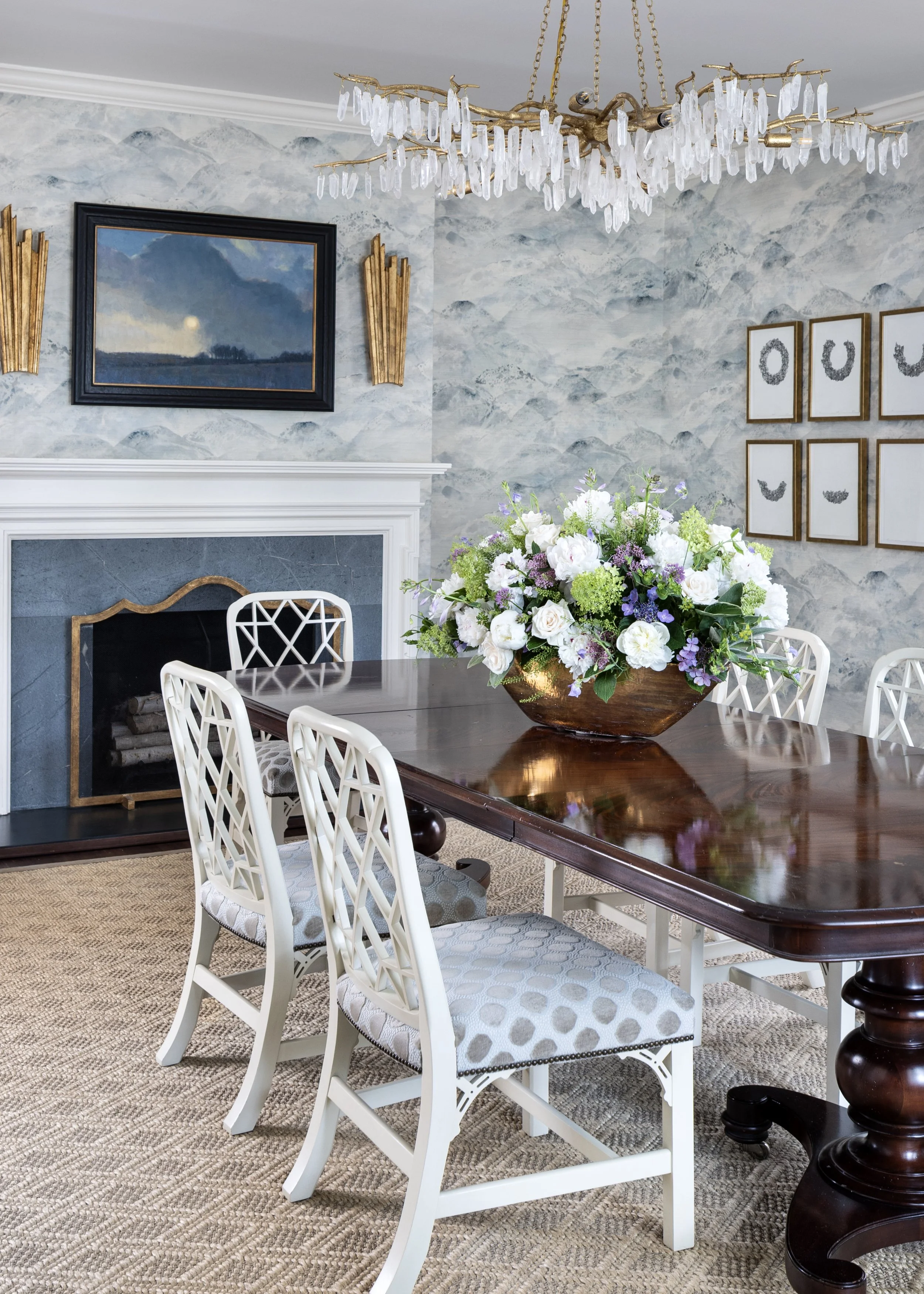 Elegant dining room featuring textured blue walls, classic millwork, curated artwork and dramatic light fixture.