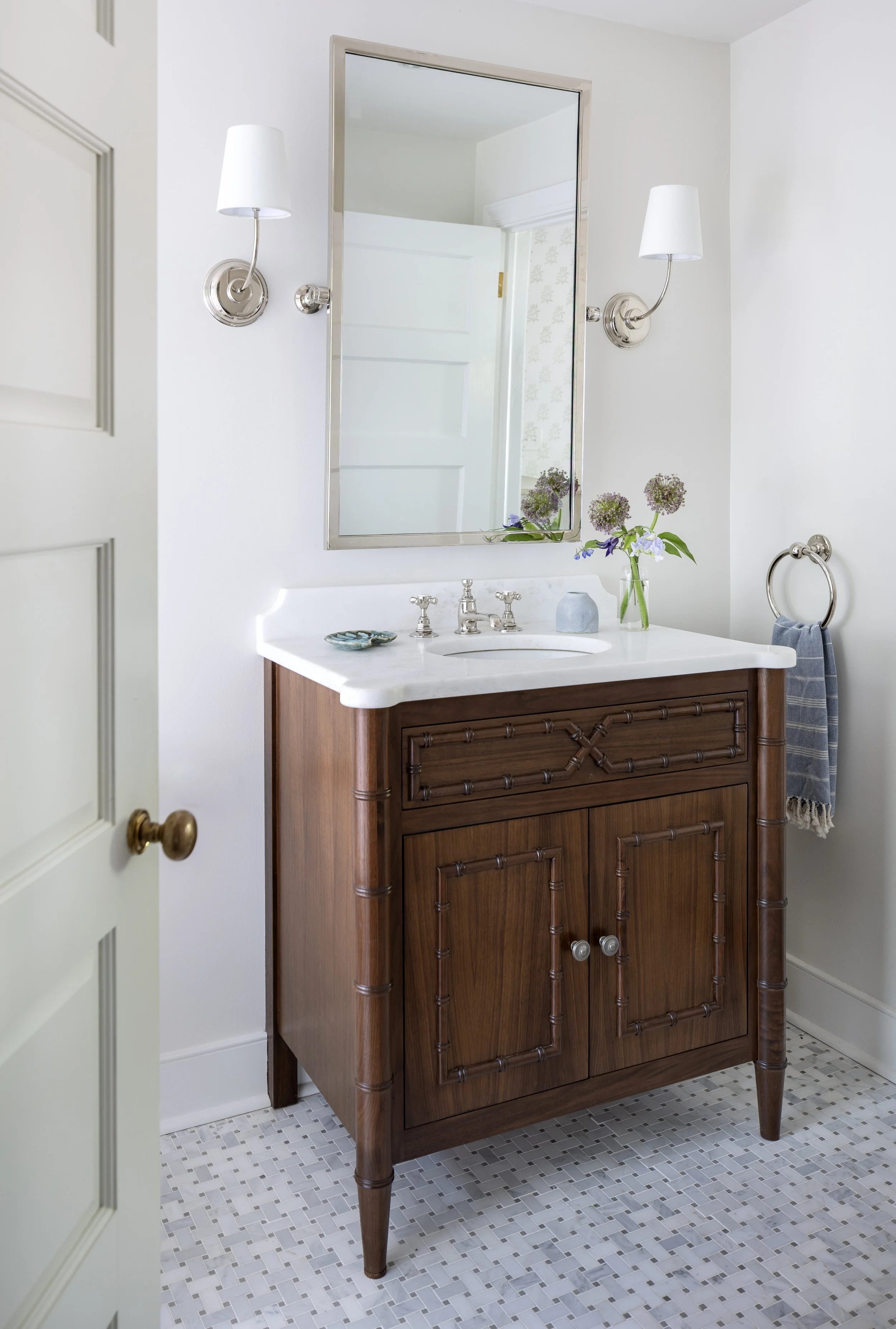 Bathroom featuring a custom wood vanity, marble countertop, patterned tile flooring, and classic lighting.