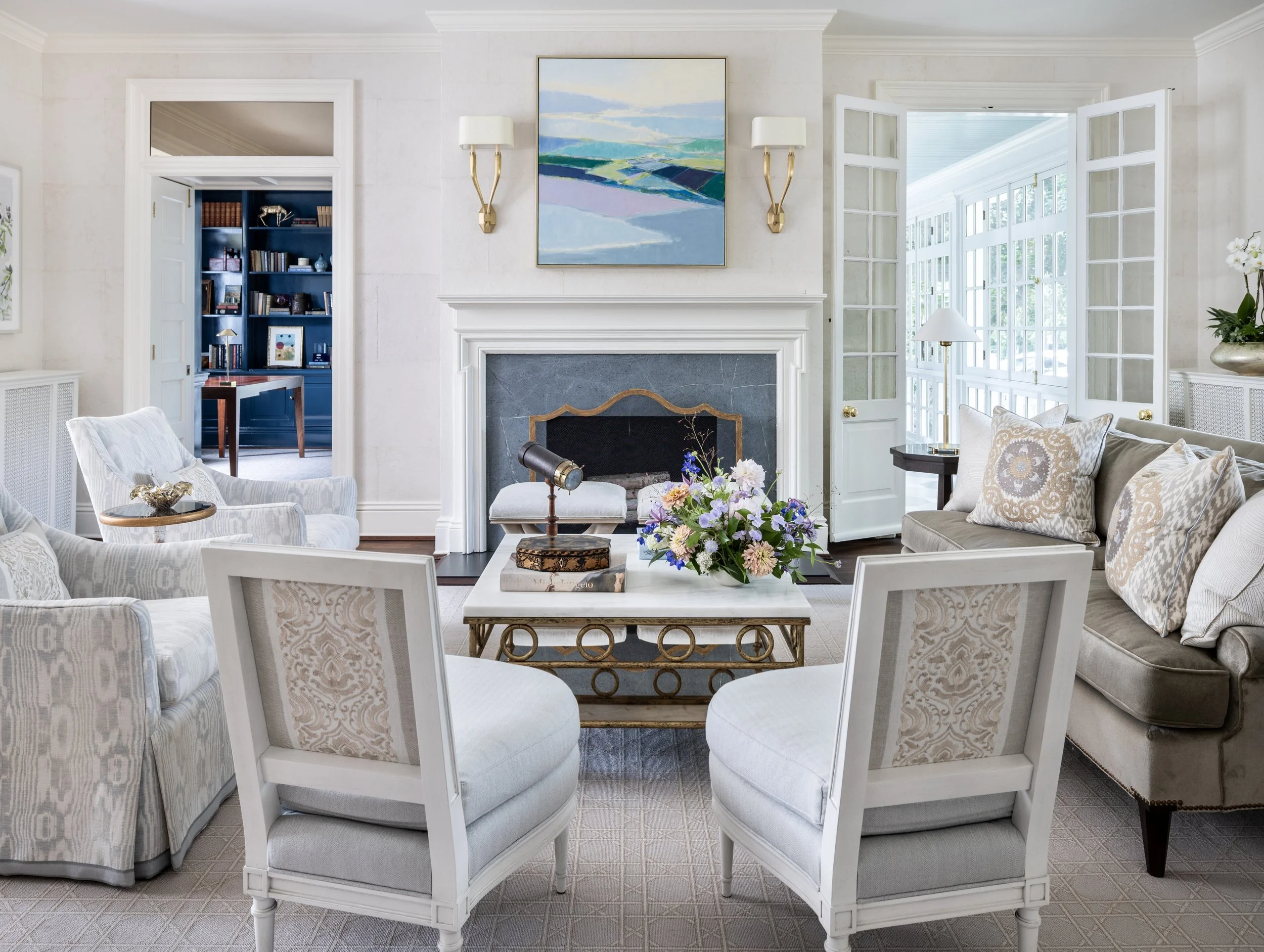 Light-filled living room with custom seating, classic fireplace, and layered furnishings designed for comfortable everyday living.