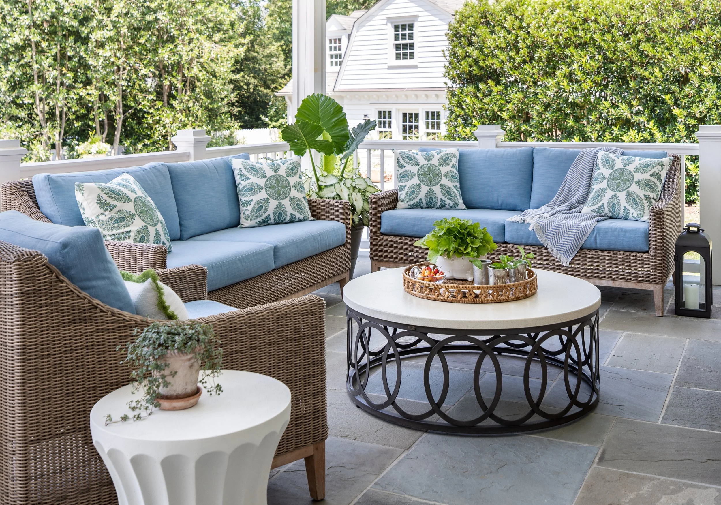 Outdoor covered porch featuring woven seating, performance fabrics, and beautifully landscaped surroundings.