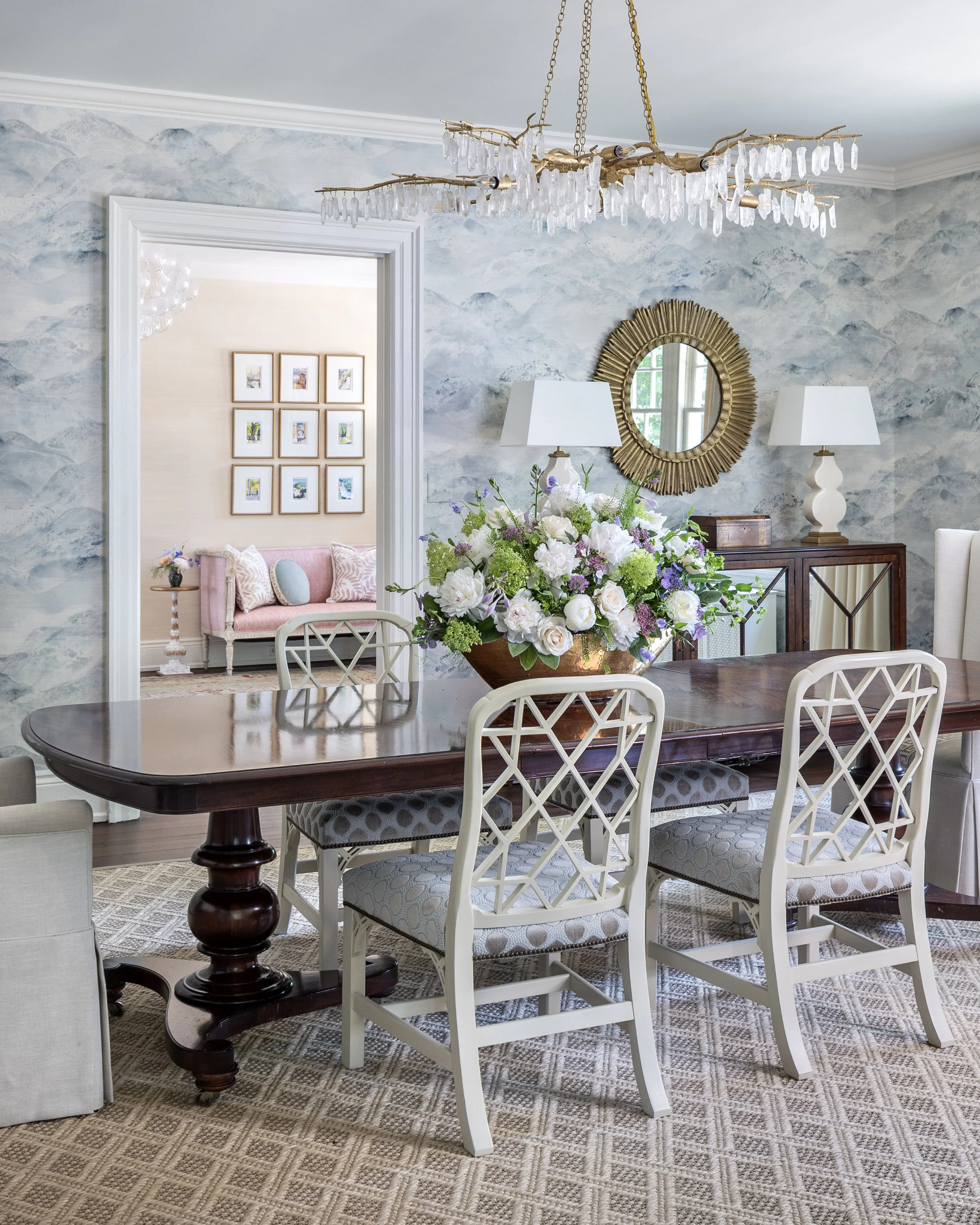 Light-filled dining room with classic furnishings, layered accessories, and views into adjacent living spaces.