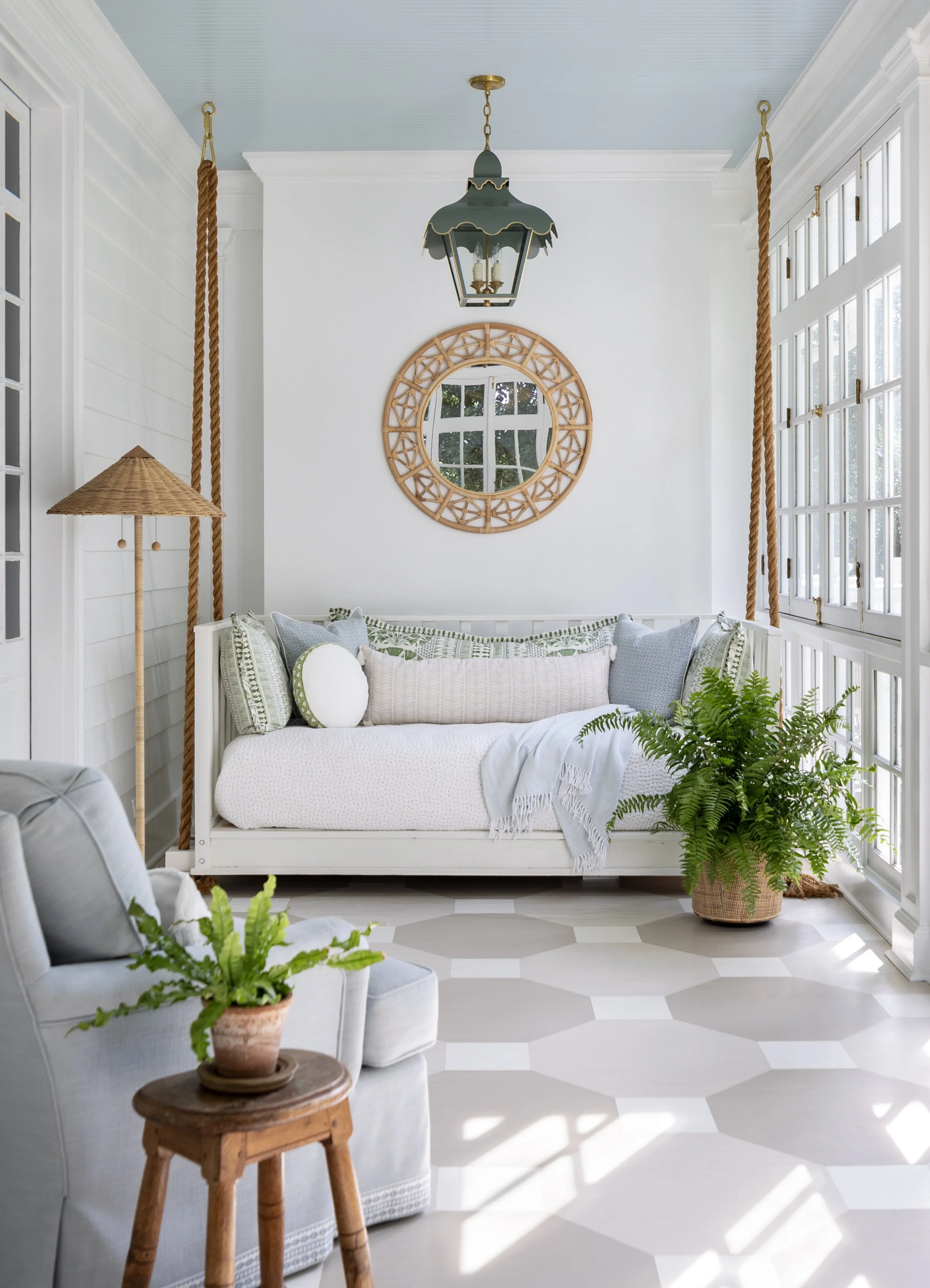 Light-filled sunroom featuring a painted blue ceiling, swing bench, painted floor, and classic architectural details.