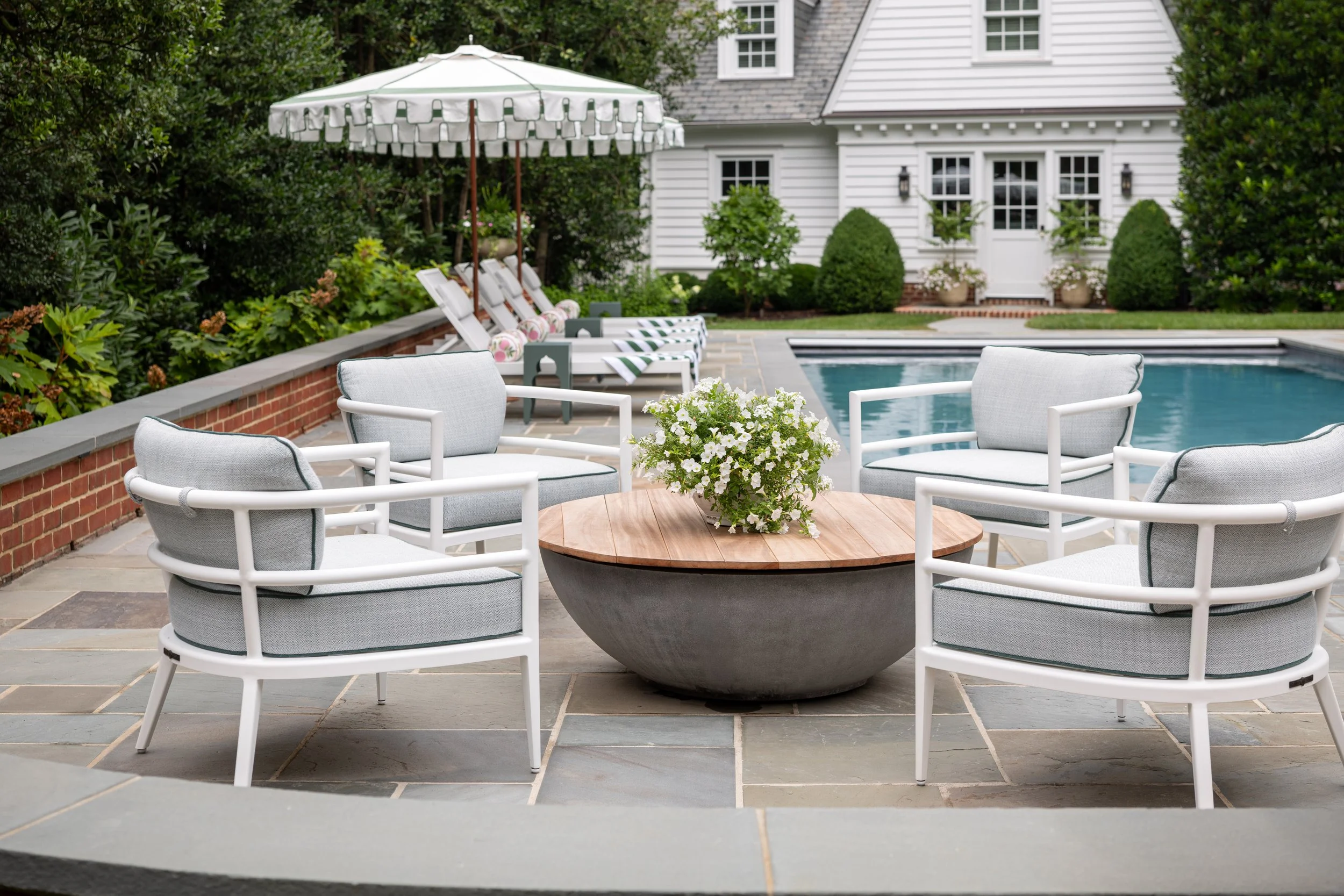 Inviting chairs surrounding a firepit by a residential pool.