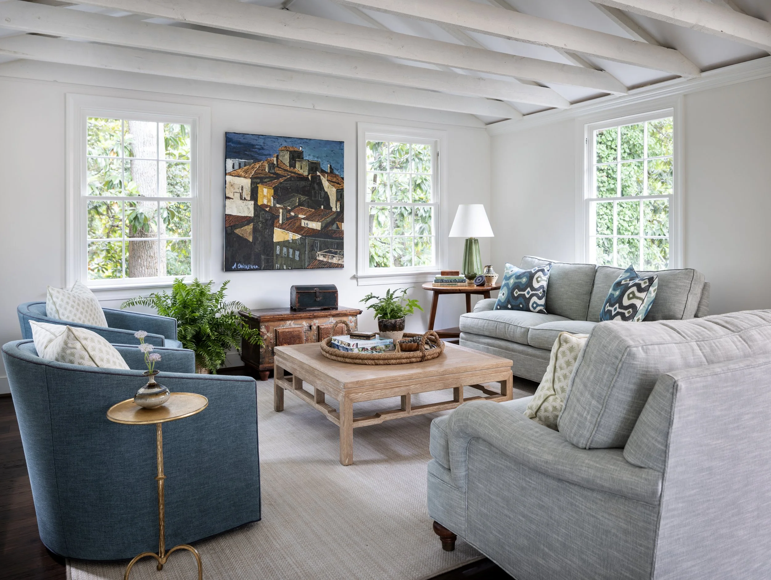 Light-filled family room featuring exposed ceiling beams, custom furnishings, layered textiles, and classic architectural details.