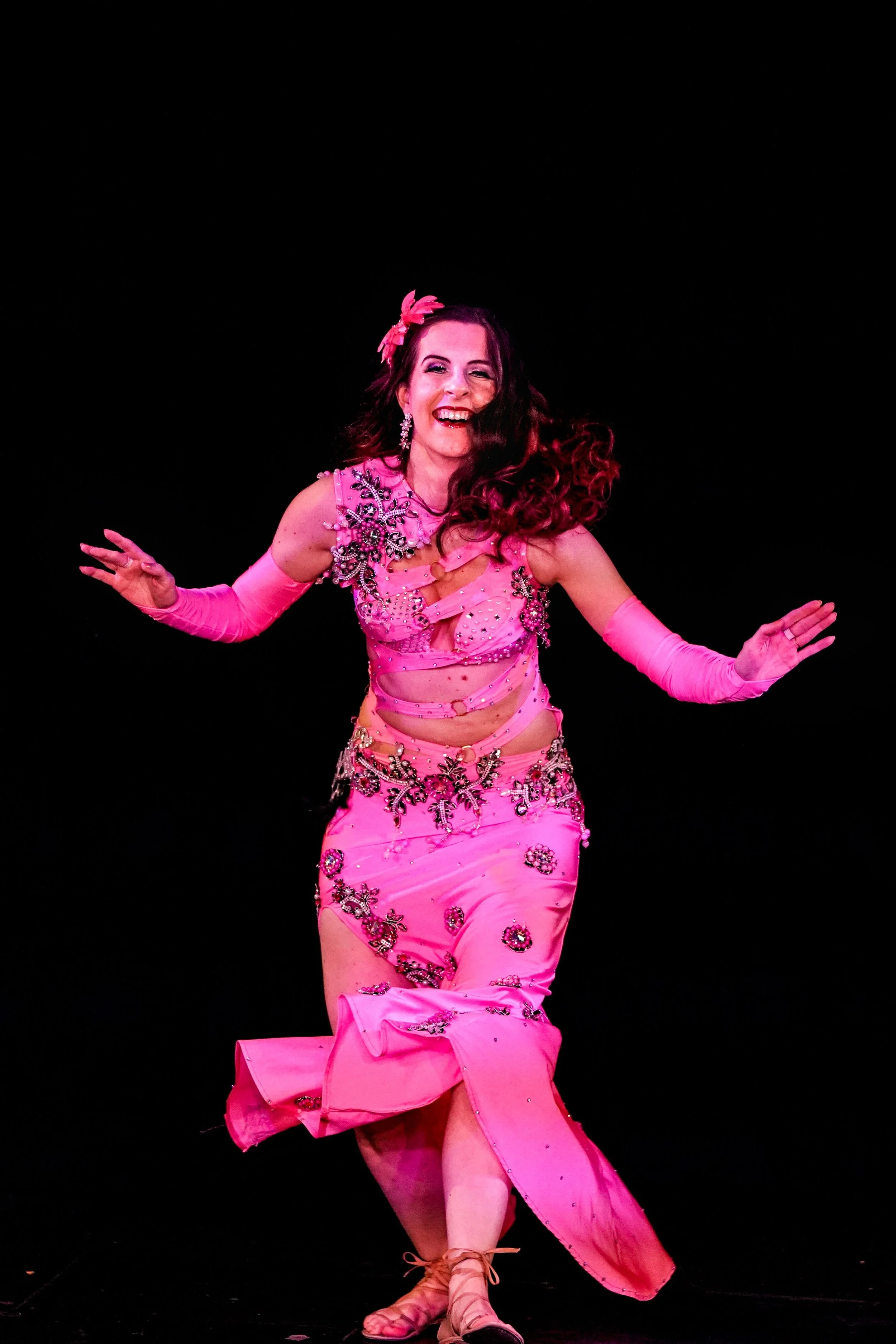 bellydancer in a neon pink dress laughs while dancing onstage in Minneapolis, Minnesota