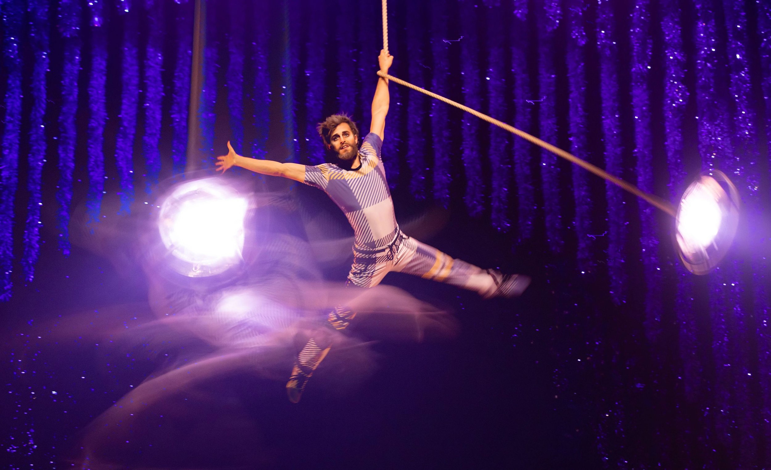 Father performing stunts on a lamp hanging from the ceiling; photo credit to Kyle Flubacker, MSG Entertainment
