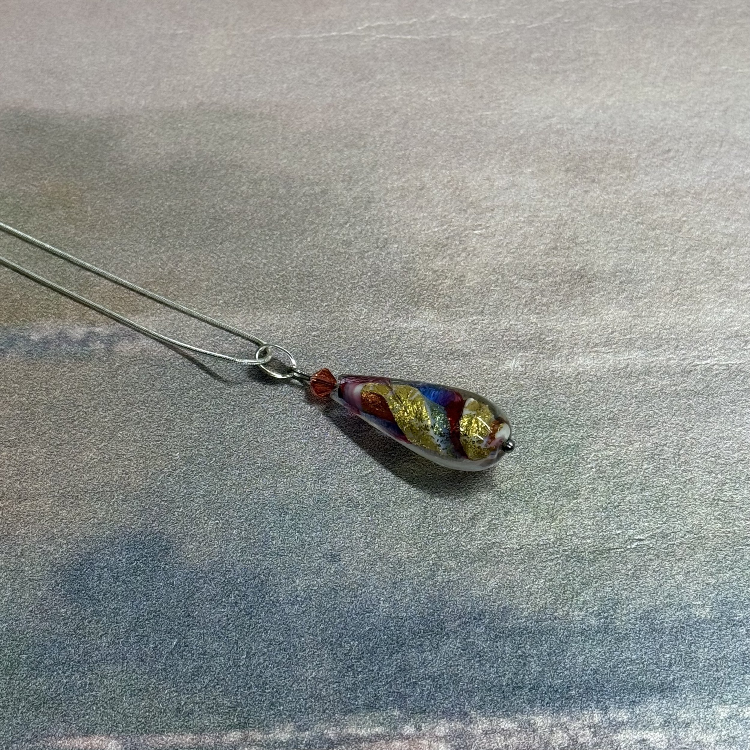 A multi coloured Murano glass teardrop pendant on a sterling silver chain