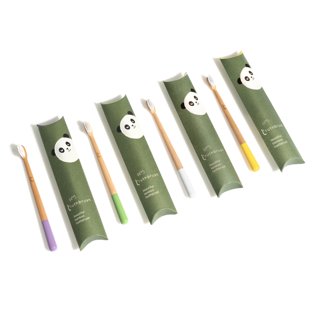 Set of five bamboo toothbrushes with panda face design on packaging, each handle has a different color tip, arranged diagonally on white background.