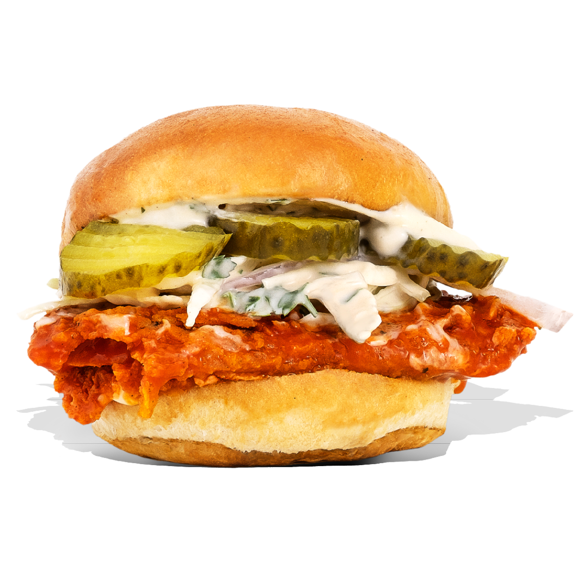 A sandwich with fried chicken, pickles, shredded lettuce, and mayonnaise on a bun.