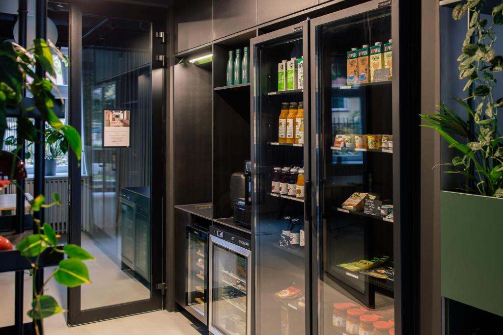 Interior view of a modern break room with a coffee station, vending machine, and refrigerated snack shelves, surrounded by green plants.