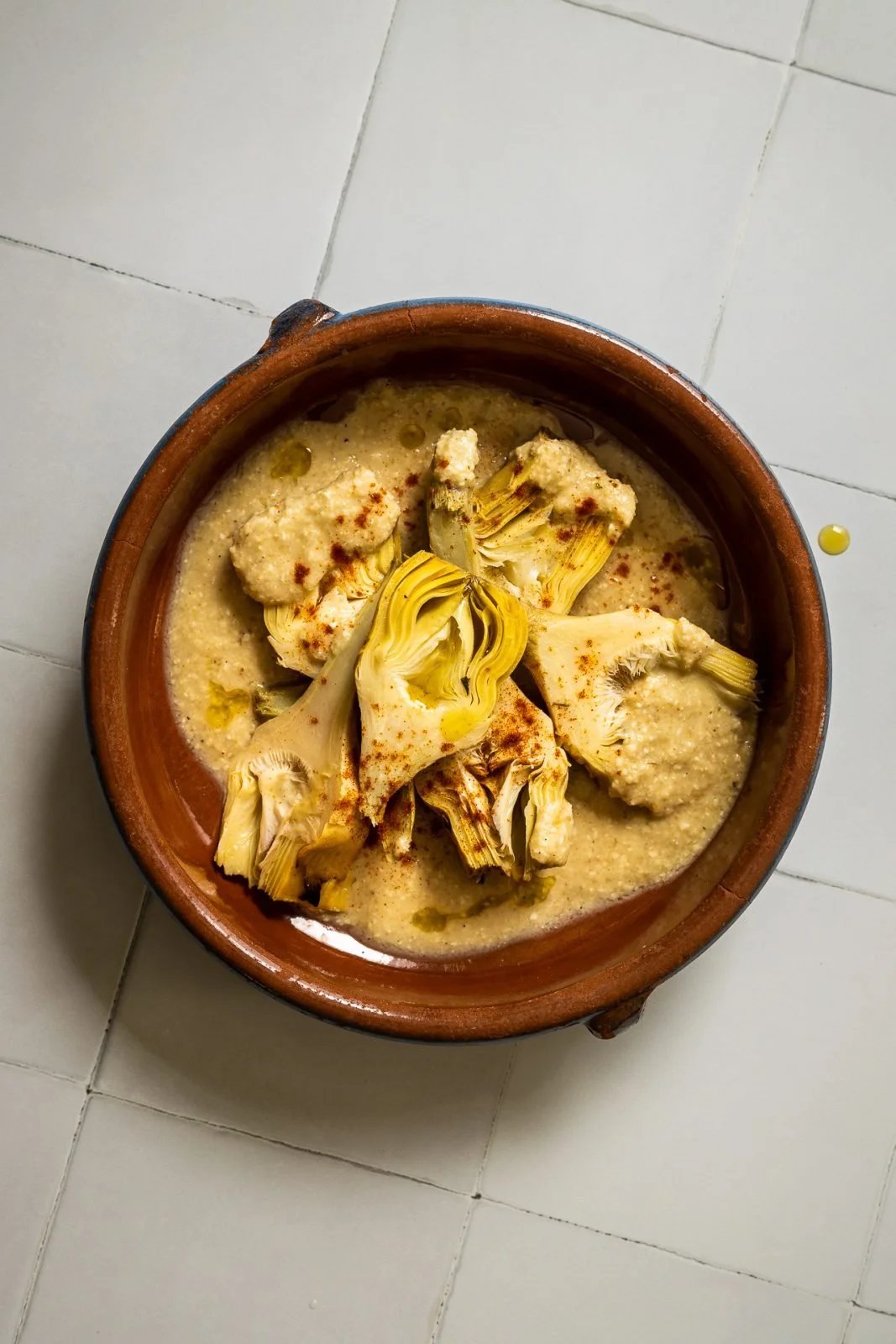 A bowl of Indian-style cauliflower curry with a creamy yellow sauce, garnished with spices.