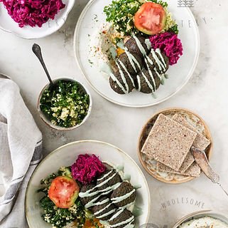 Salad with sliced beets and a hard-boiled egg, with a side of bread slices and a small bowl of green herb dressing.