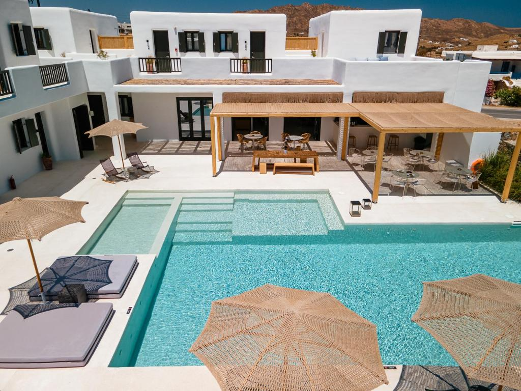 A modern white building with a swimming pool and outdoor seating areas, including umbrellas and lounge chairs.