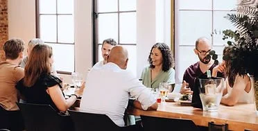 Group of eight people having a meeting or discussion around a table in a bright room.