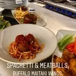 Bowl of spaghetti with meatballs, served with a side salad of lettuce and tomatoes.