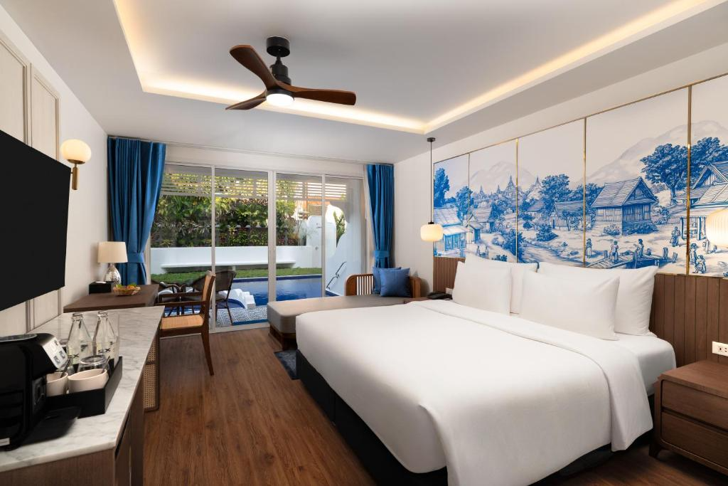 Hotel room with large bed, blue curtains, sliding glass doors to balcony, wall art, and modern decor.