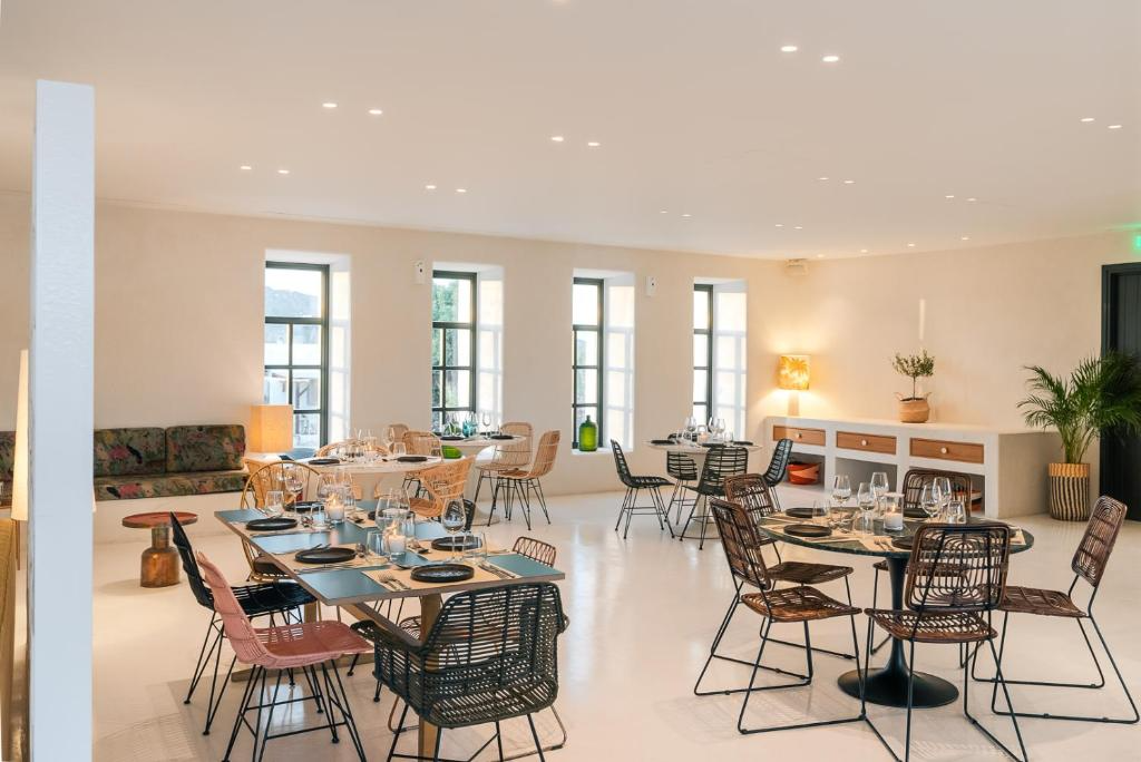 Empty restaurant dining area with multiple tables, chairs, and table settings, illuminated by natural and artificial light, with decorative plants and minimal decor.